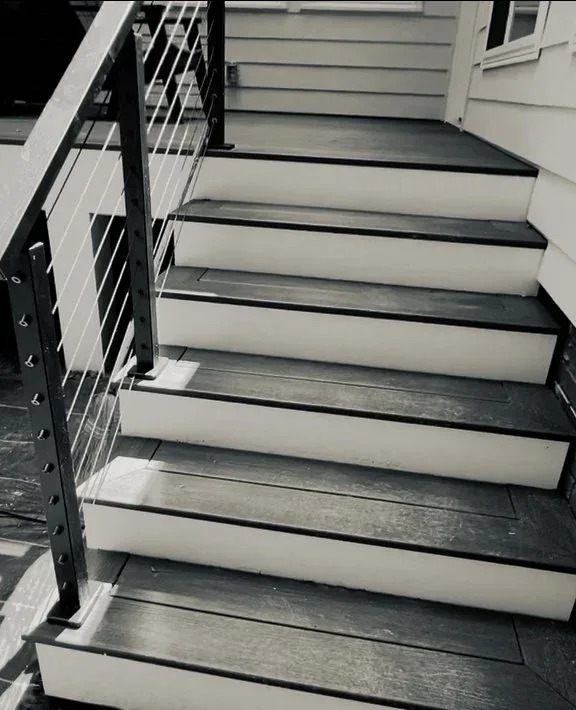 Custom deck staircase with a black metal frame and cable railing
