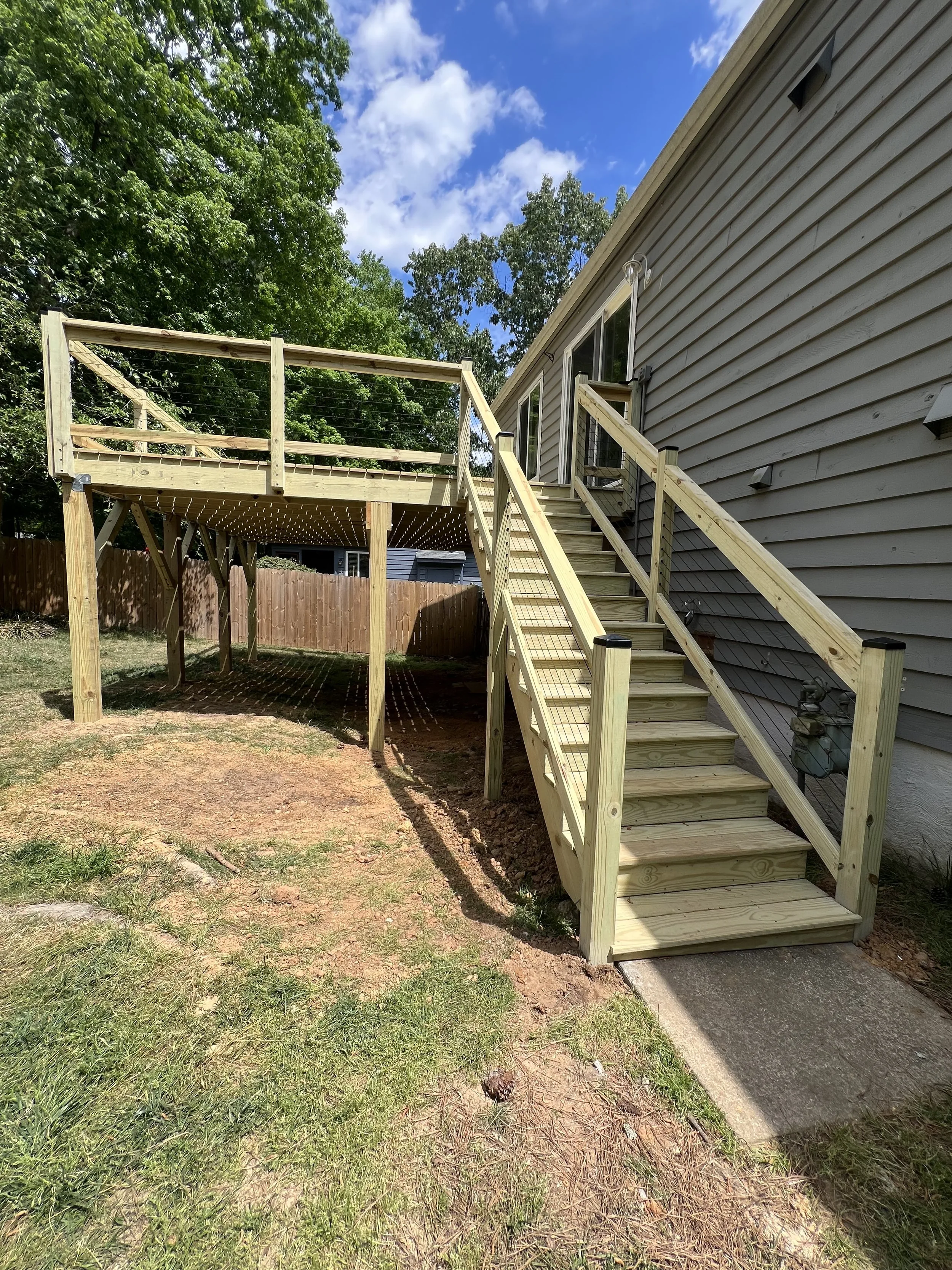 Newly built raised wood deck with railing and a staircase