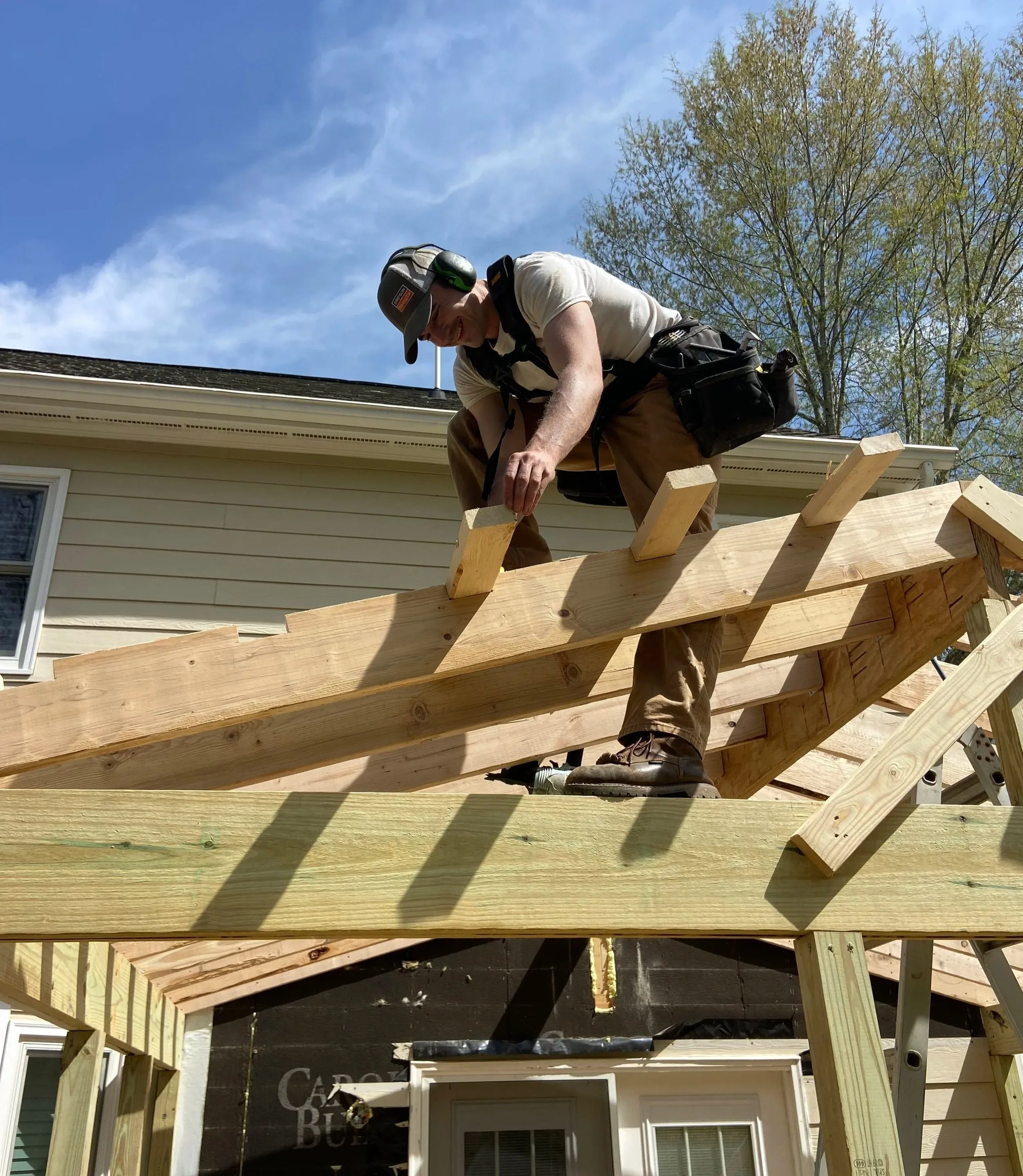 Craftsman framing a wood pergola roof during a backyard build