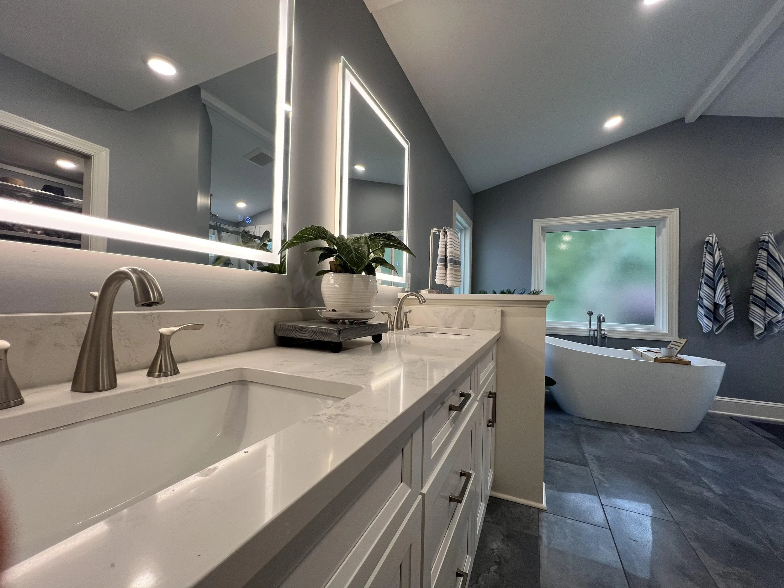 Remodeled bathroom with a double-sink vanity and lit mirrors